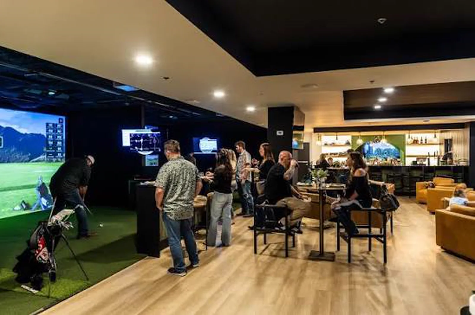 Members gathered around the simulator bays during an event at 1872 Golf Club