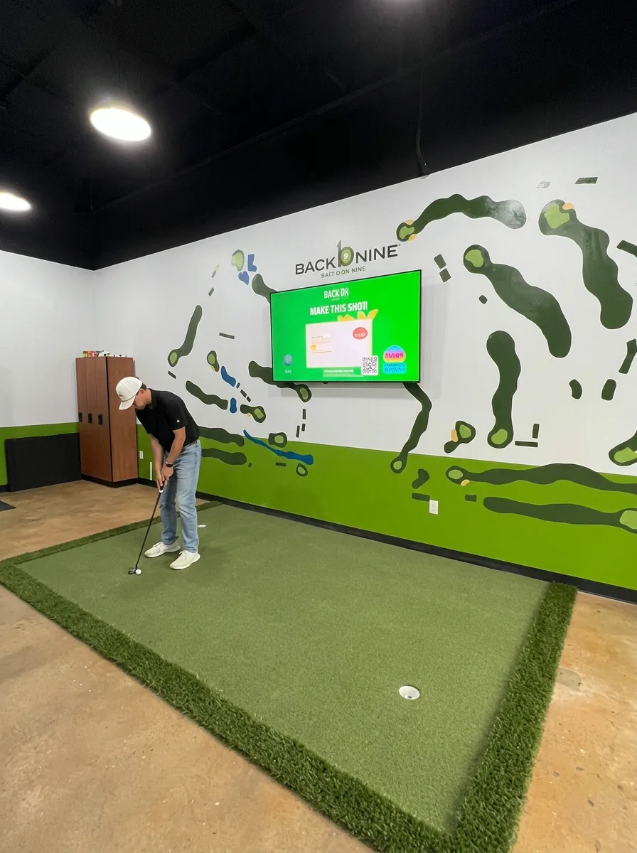 Golfer practicing on the indoor putting green at The Back Nine East Austin